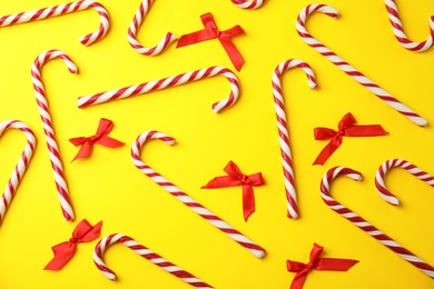 Photo of Flat lay composition with candy canes and red bows on yellow background