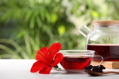 Photo of Delicious hibiscus tea and flowers on white wooden table outdoors, space for text