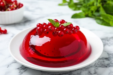 Photo of Delicious fresh red jelly with berries and mint on marble table