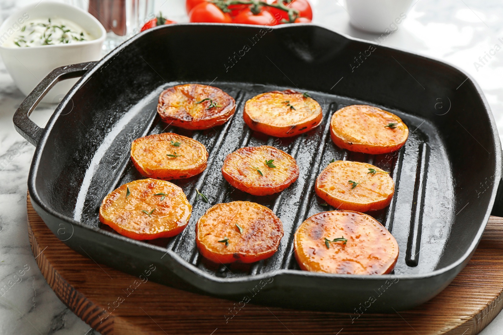 Photo of Grill pan with sweet potato fries on marble table, closeup