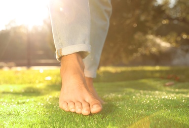 Photo of Man walking barefoot on fresh green grass, closeup