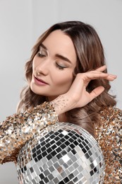 Photo of Beautiful woman in golden dress with disco ball posing on white background