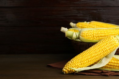 Photo of Tasty fresh corn cobs on wooden table, space for text