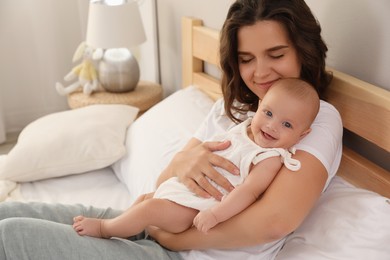 Photo of Happy young mother with her cute baby on bed at home