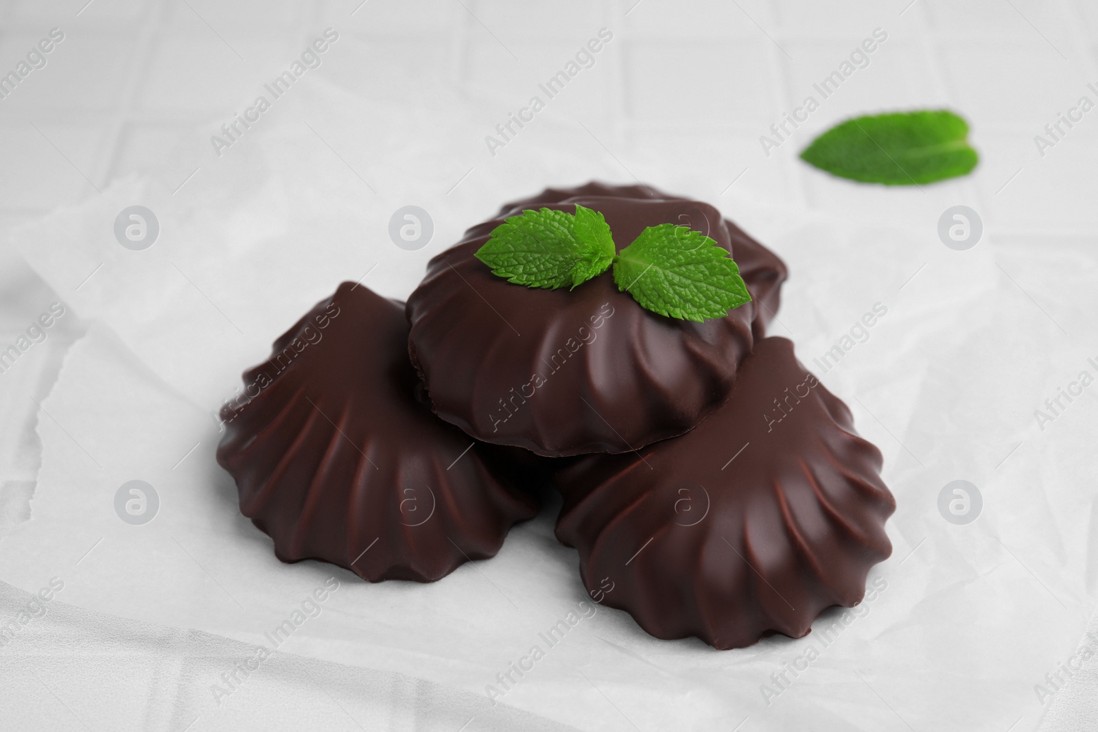 Photo of Delicious chocolate covered zephyrs with mint on white table