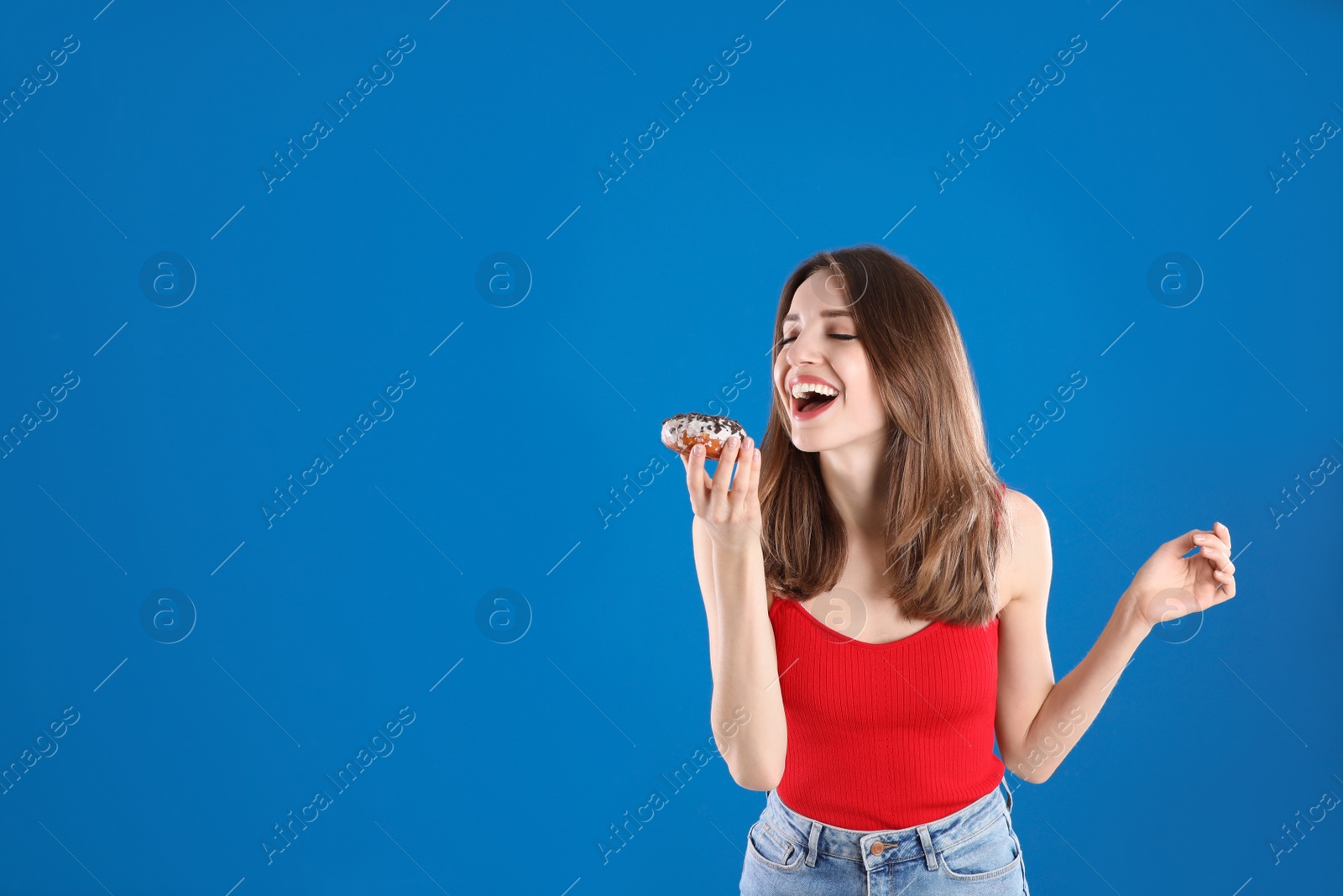 Photo of Beautiful young woman with donut on blue background. Space for text