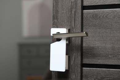 Wooden door with blank hanger on metal handle, closeup