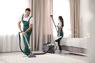 Team of janitors cleaning bedroom with professional equipment