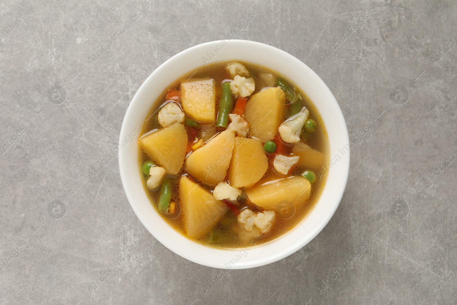 Photo of Bowl of delicious turnip soup on light grey table, top view