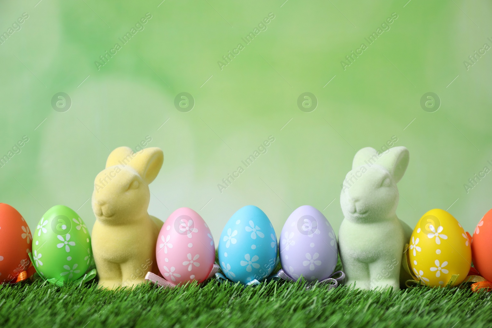 Photo of Easter bunnies and painted eggs on green grass