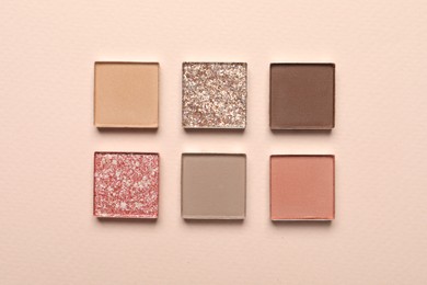 Different beautiful eye shadows on beige background, flat lay