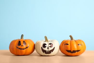 Photo of Pumpkins with scary faces on light blue background, space for text. Halloween decor