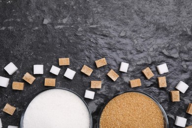 Photo of Different types of sugar in bowls on dark gray textured table, flat lay. Space for text