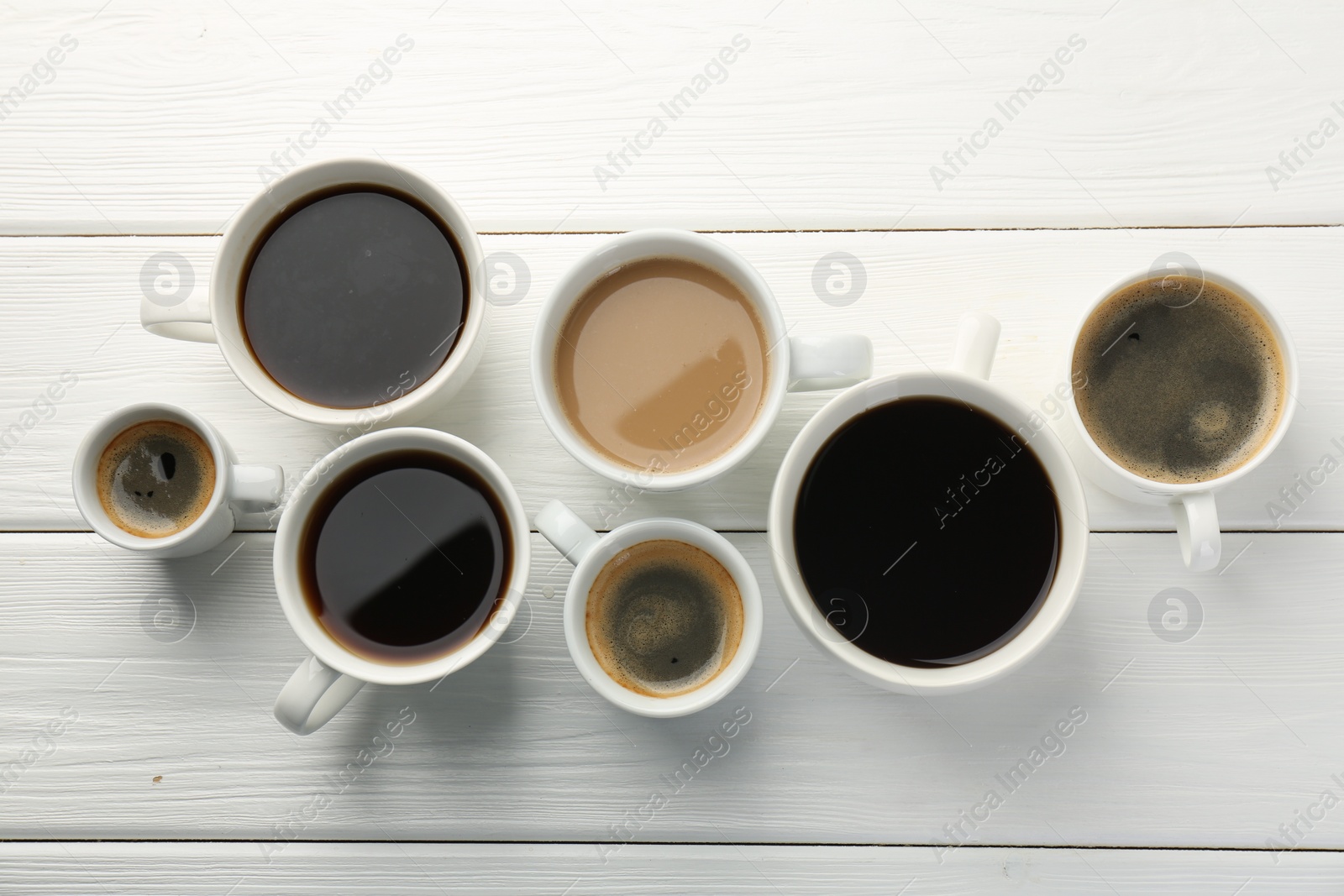 Photo of Different coffee drinks in cups on white wooden table, flat lay