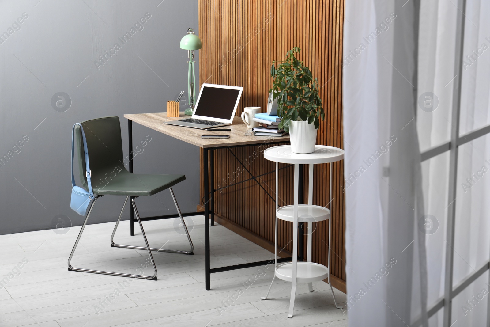 Photo of Stylish workplace interior with laptop on table near wooden wall. Space for text