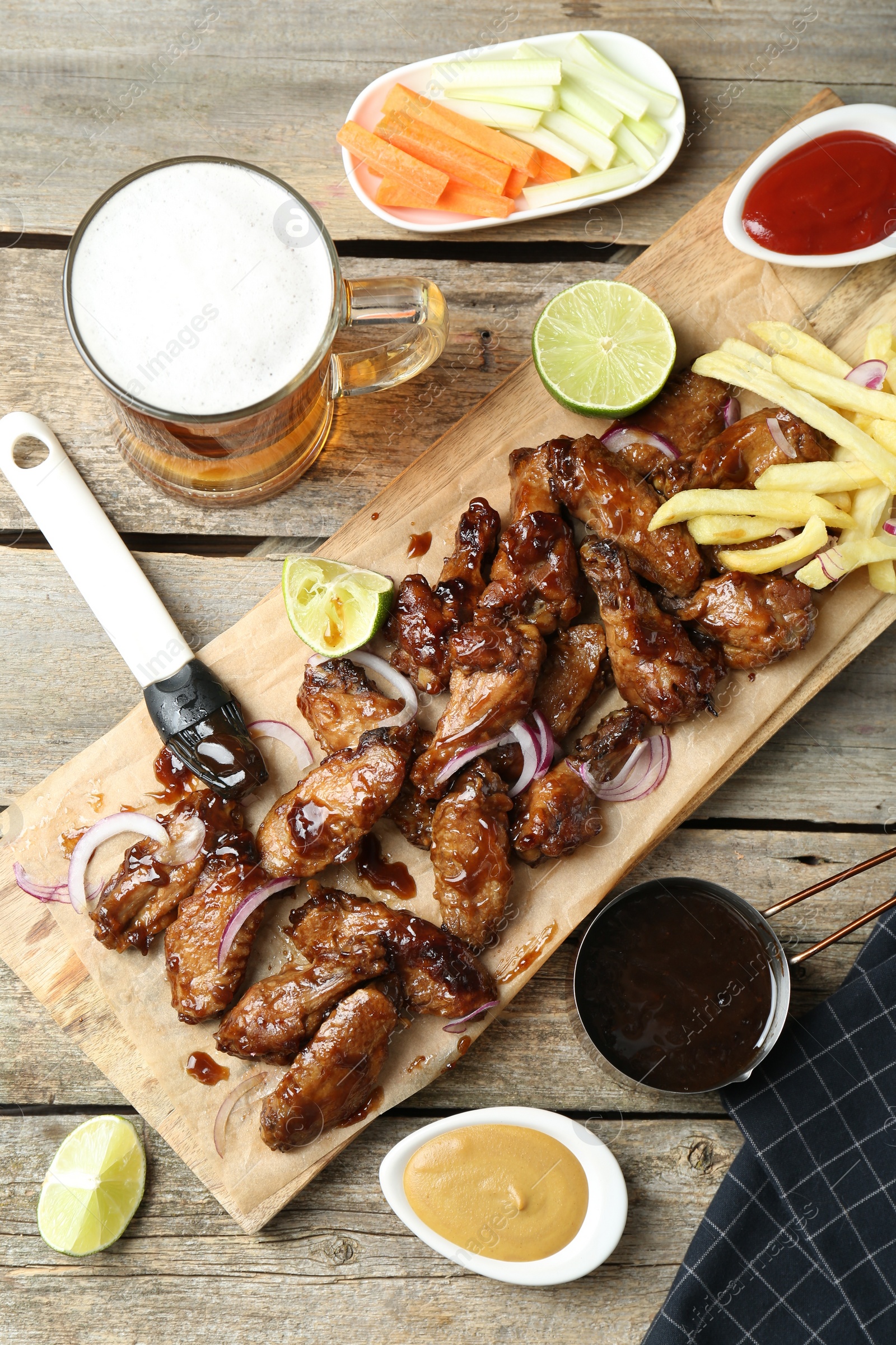 Photo of Tasty roasted chicken wings served with beer on wooden table, flat lay
