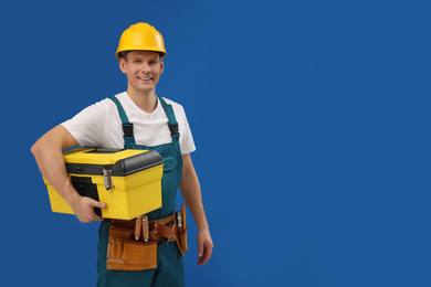 Handsome carpenter with tool box on blue background. Space for text