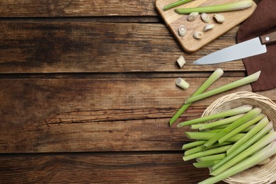 Photo of Fresh lemongrass, knife and cutting board on wooden table, flat lay. Space for text