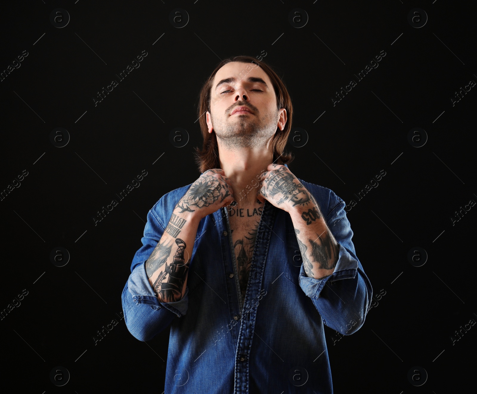 Photo of Young man with tattoos on body against black background