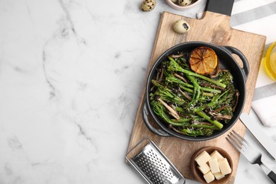 Tasty cooked broccolini, mushrooms and lemon on white marble table, flat lay. Space for text