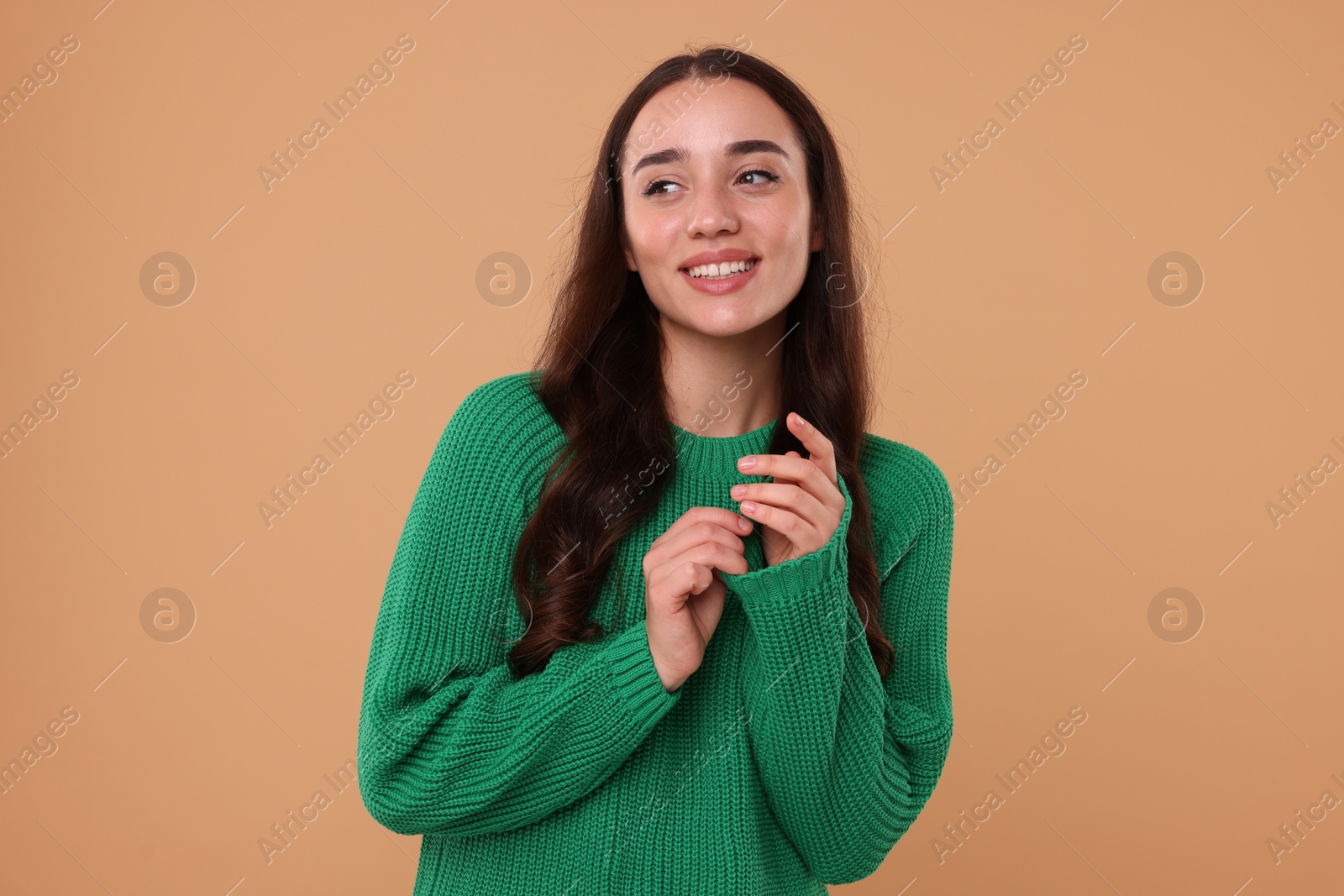 Photo of Beautiful young woman in stylish warm sweater on beige background