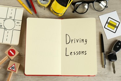 Photo of Flat lay composition with workbook for driving lessons on wooden background. Passing license exam