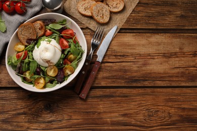 Photo of Delicious burrata salad with colorful cherry tomatoes, croutons and arugula served on wooden table, flat lay. Space for text