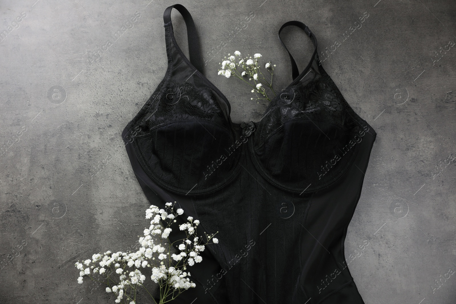 Photo of Elegant black plus size women's underwear and gypsophila flowers on grey background, flat lay