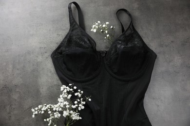 Elegant black plus size women's underwear and gypsophila flowers on grey background, flat lay