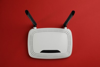 Photo of Modern Wi-Fi router on red background, top view