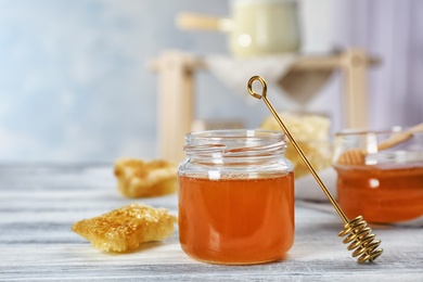 Photo of Jar of honey, dipper and honeycombs on table