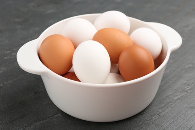 Photo of Unpeeled boiled eggs in saucepan on dark grey table, closeup