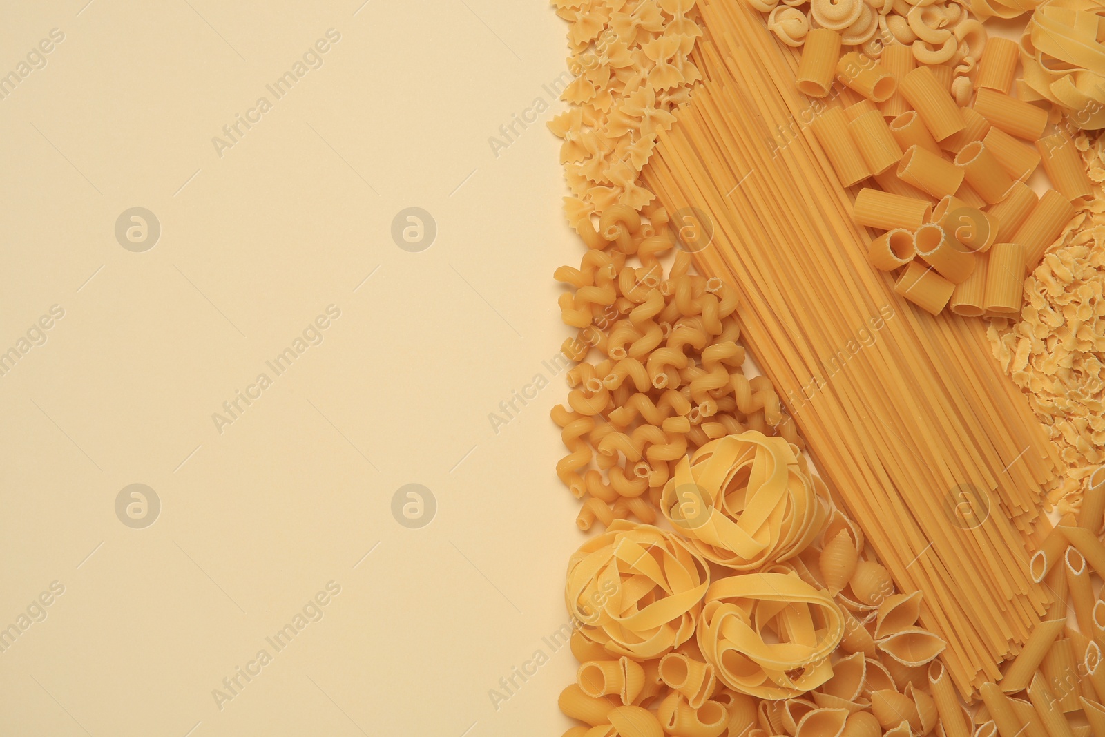 Photo of Different types of pasta on beige background, flat lay. Space for text