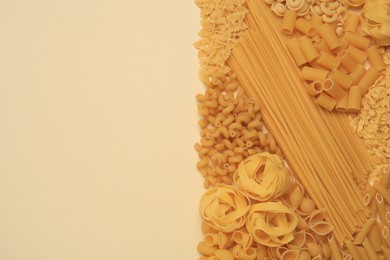 Photo of Different types of pasta on beige background, flat lay. Space for text