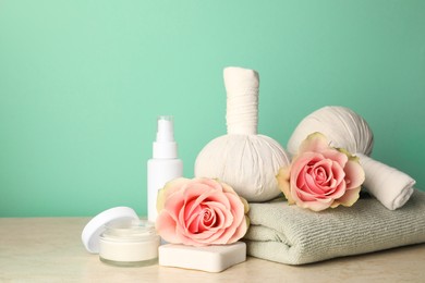 Composition with different spa products and roses on beige table against turquoise background. Space for text