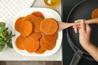 Photo of Woman cooking breaded cutlets in frying pan on stove, top view