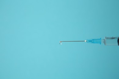 Photo of Medical syringe on light blue background, closeup. Space for text