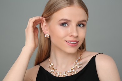 Photo of Beautiful young woman with elegant jewelry on gray background