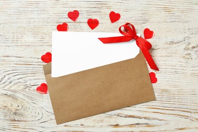 Photo of Blank card, envelope and red hearts on white wooden background, flat lay with space for text. Valentine's Day celebration