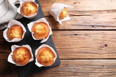 Delicious sweet muffins on wooden table, flat lay. Space for text