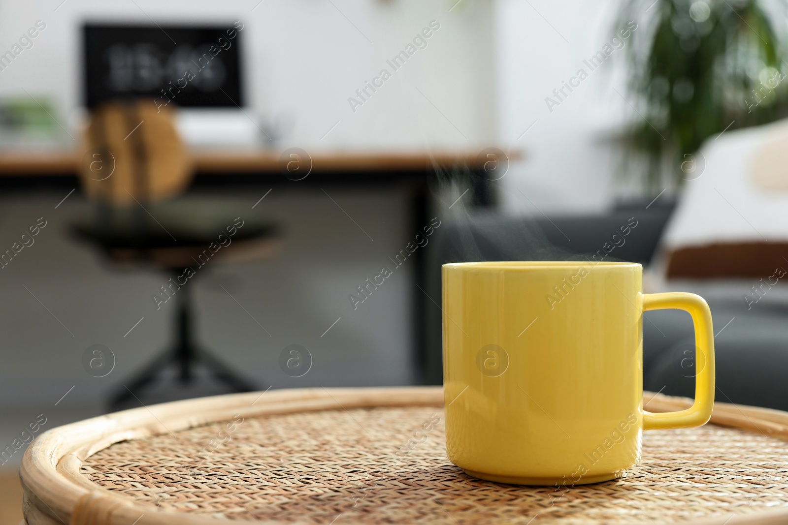 Photo of Ceramic mug with hot drink on wicker table indoors. Mockup for design