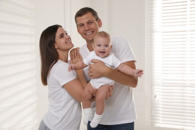 Happy family. Couple with their cute baby near window indoors
