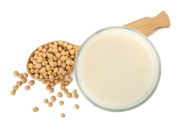 Glass of fresh soy milk and spoon with beans on white background, top view