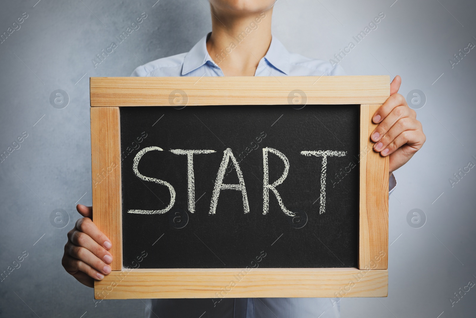 Photo of Woman holding blackboard with word Start on light background, closeup