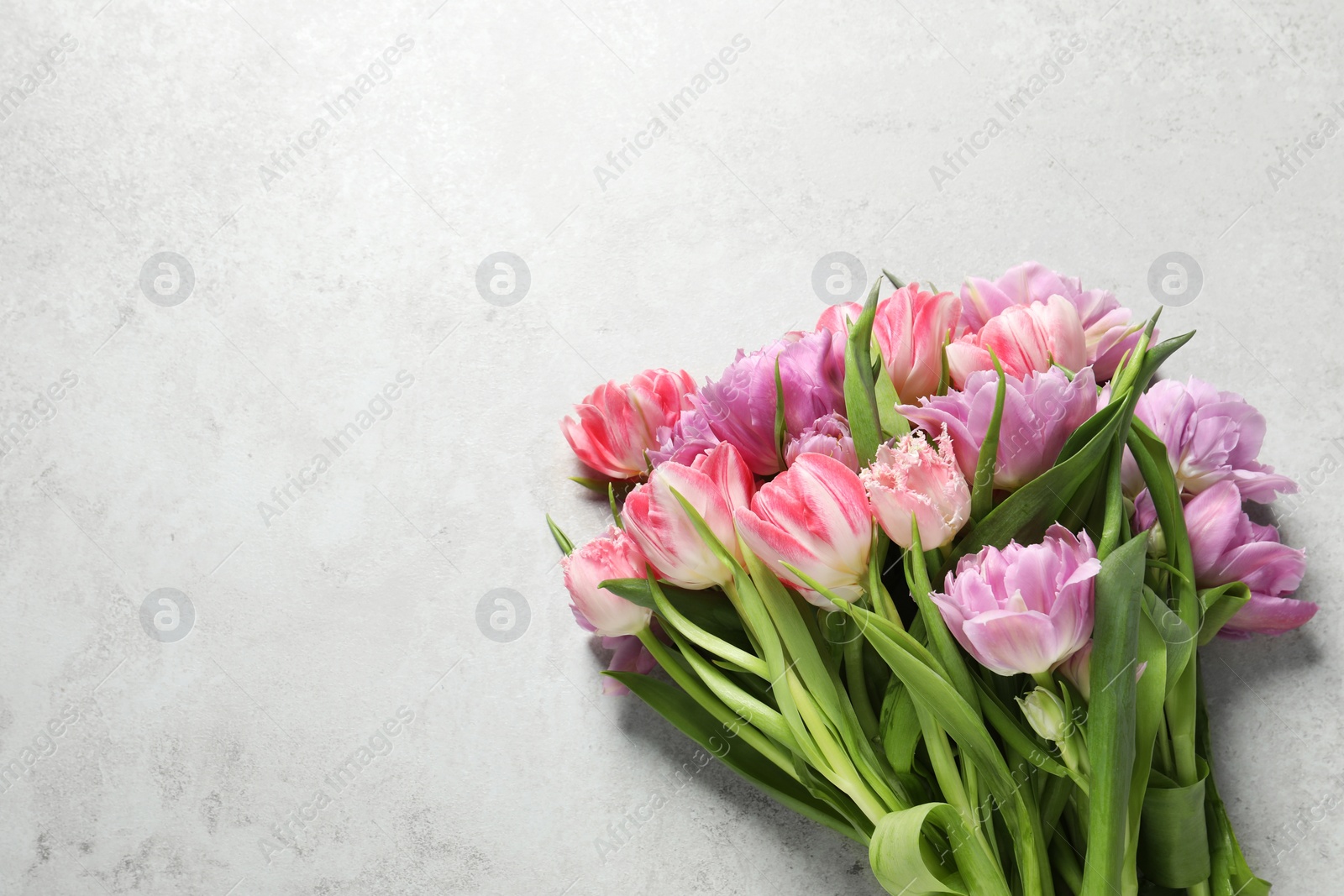Photo of Beautiful bouquet of colorful tulip flowers on light grey table, top view. Space for text