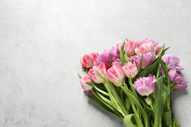 Beautiful bouquet of colorful tulip flowers on light grey table, top view. Space for text