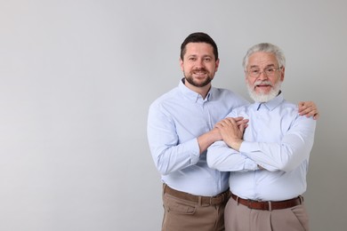 Happy son and his dad on gray background, space for text