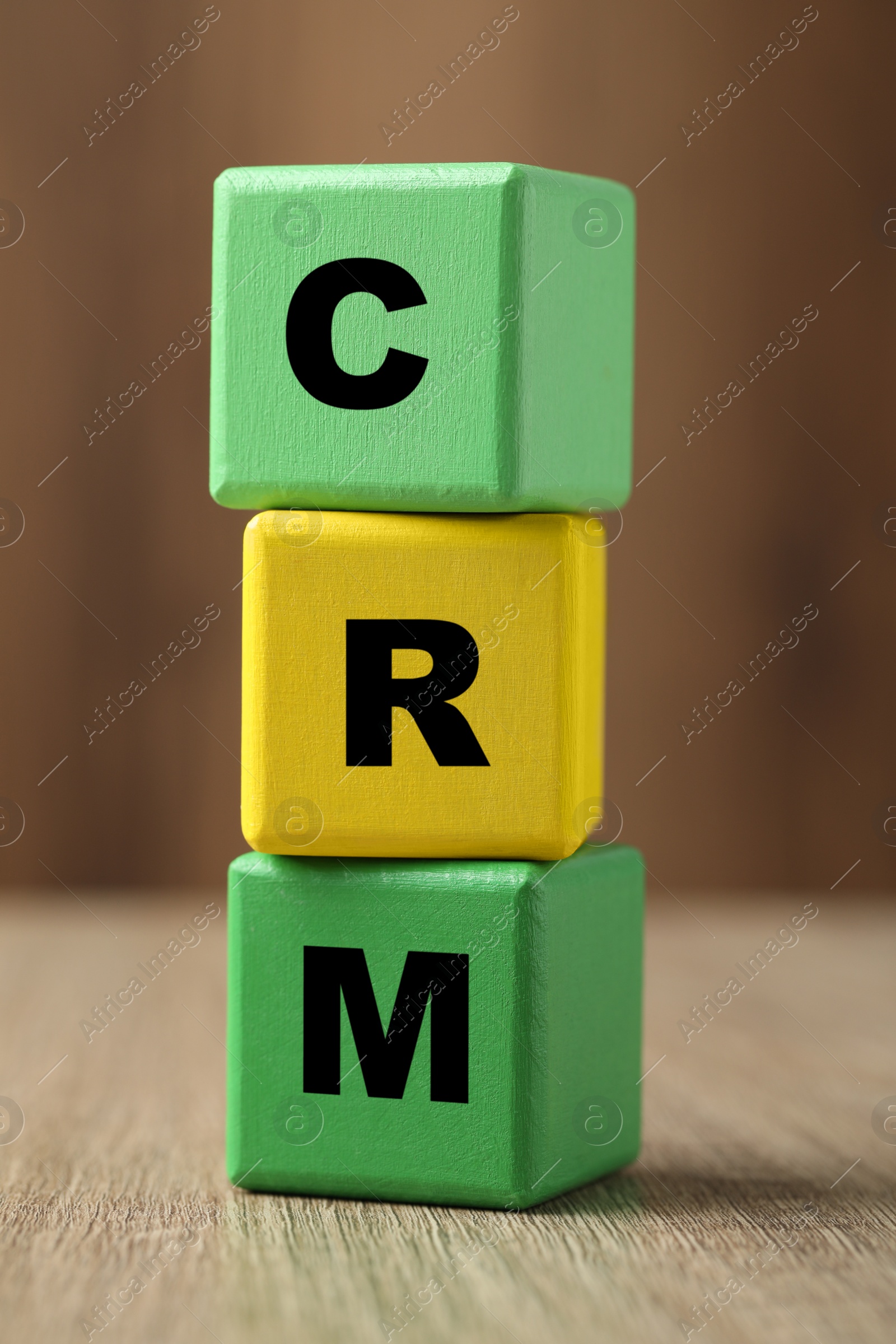 Photo of Abbreviation CRM of cubes on wooden table, closeup. Customer Relationship Management