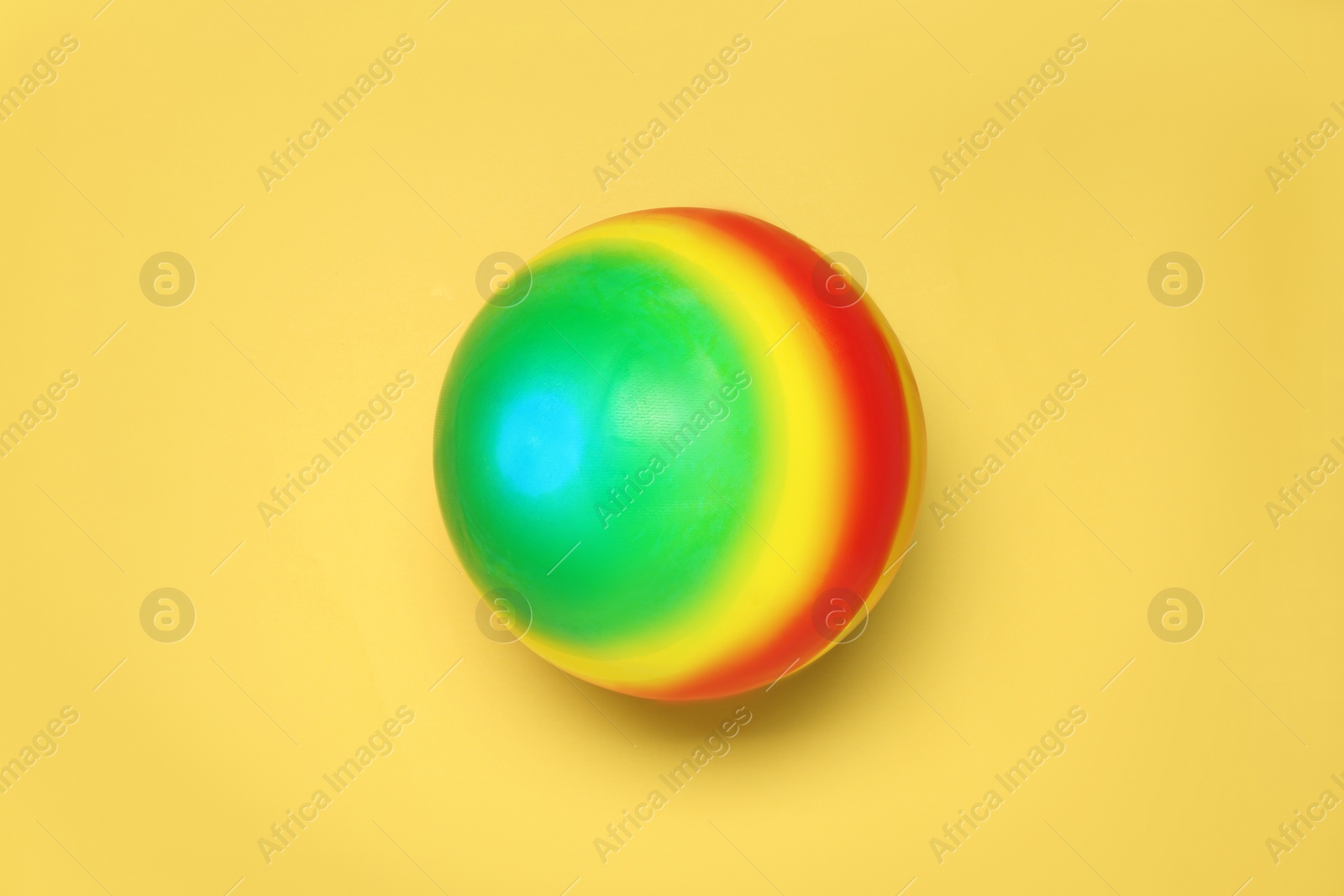 Photo of New bright kids' ball on yellow background, top view