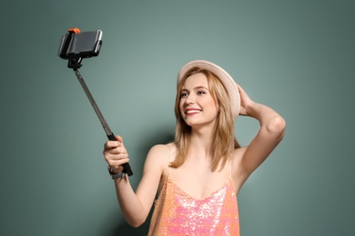 Photo of Attractive young woman taking selfie on color background